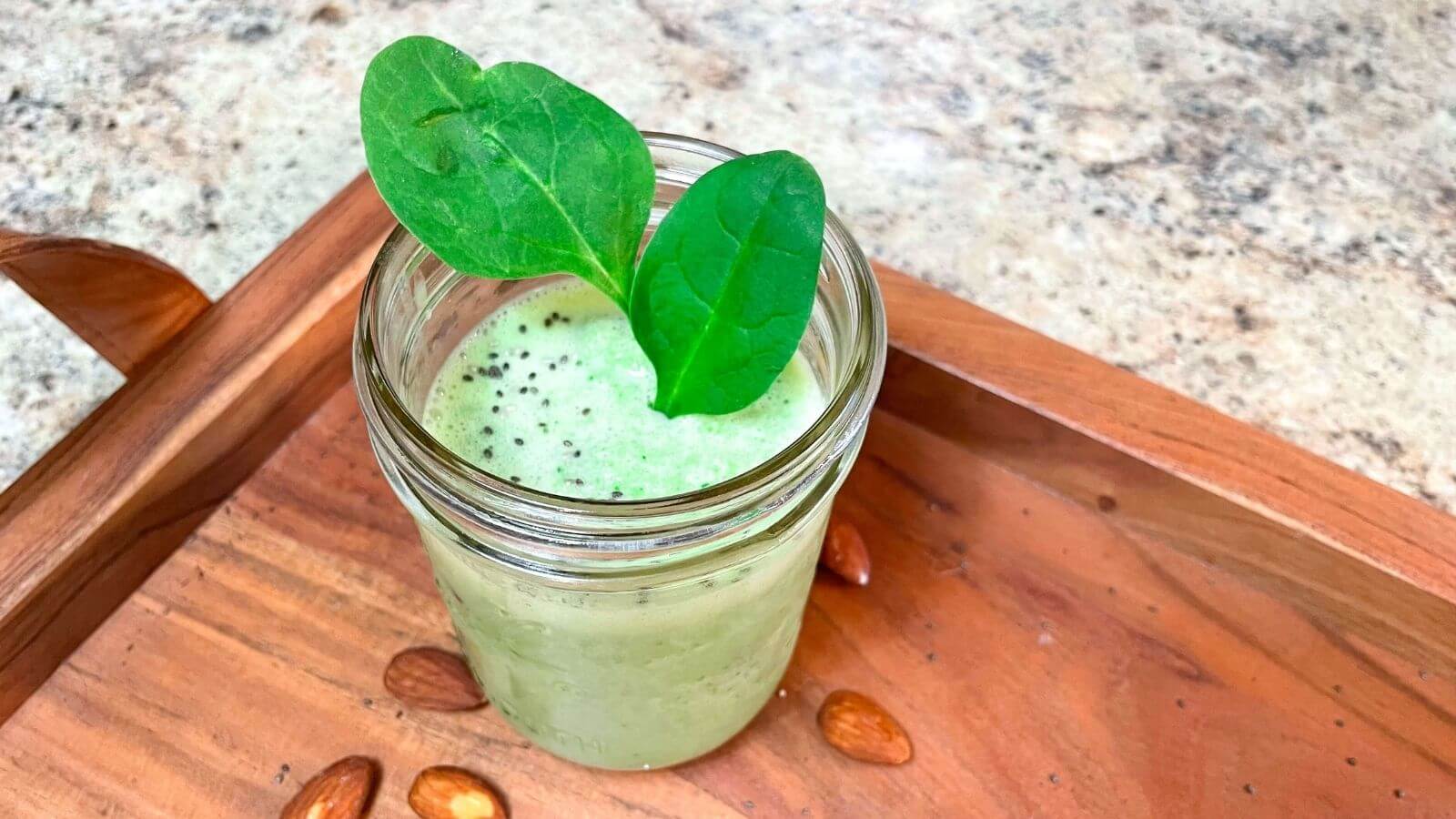 mason jar filled with green protein shake, garnished with spinach leaves