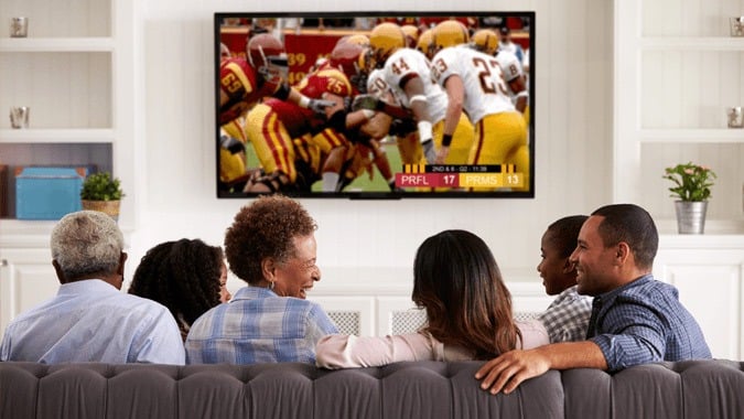 Friends watching sports on a couch while they enjoy healthy foods.