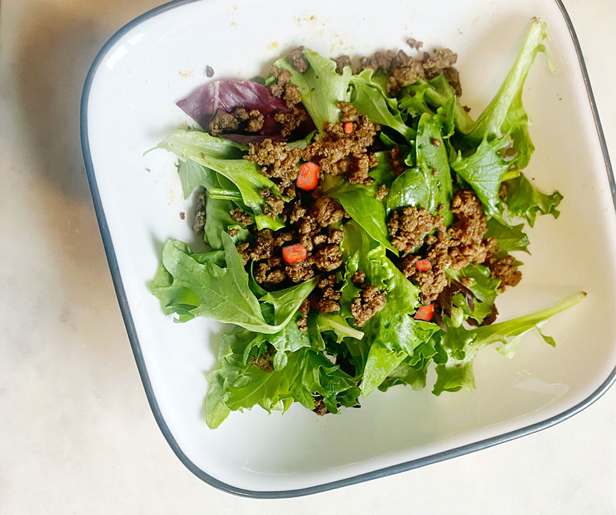 bowl filled with mixed greens topped with ground beef and chopped veggies