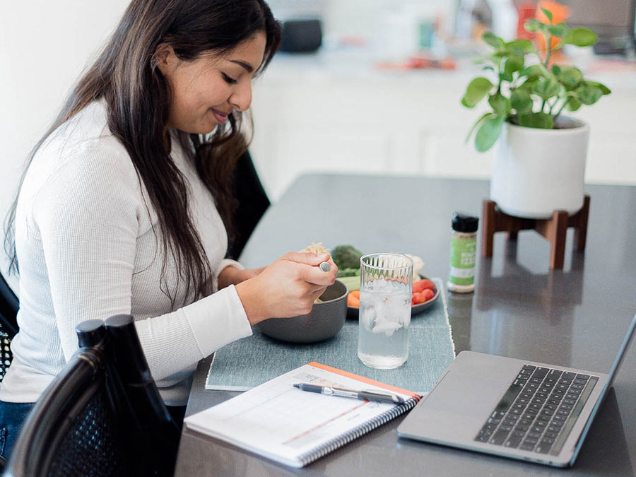Woman at her table watching a hacking health webinar by Profile Plan.
